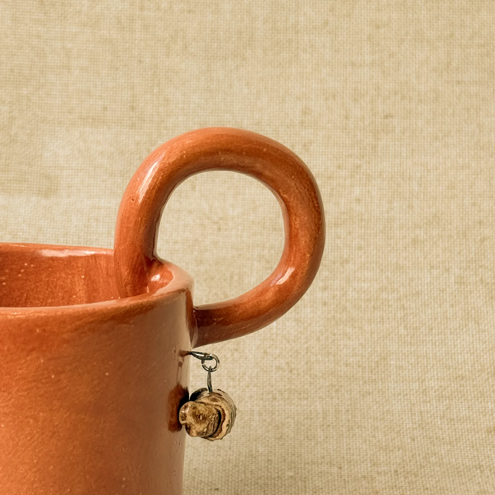 Caneca artesanal terracota com pequeno detalhe pendente